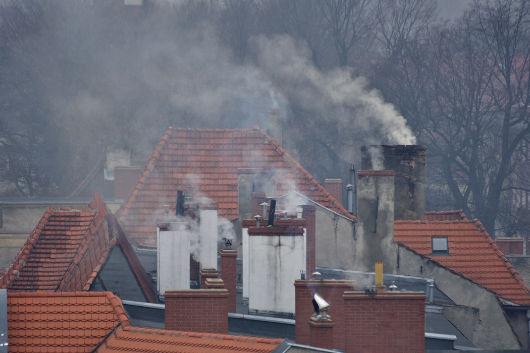 Na rudych szpiczastych dachach są kominy z których leci szary dym