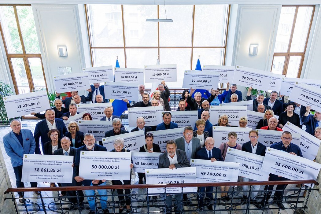 Grupa ludzi w garniturach pozuje z swoimi czekami, które dostali