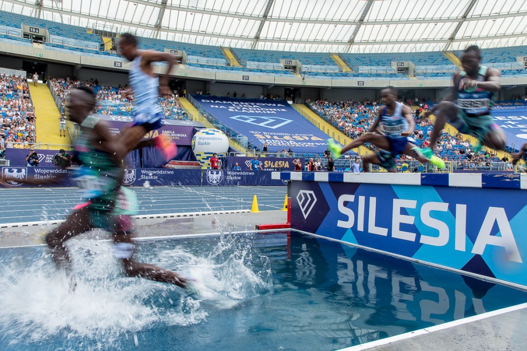 wysportowani czarnoskórzy sportowcy skaczący przez tor przeszkod na stadionie